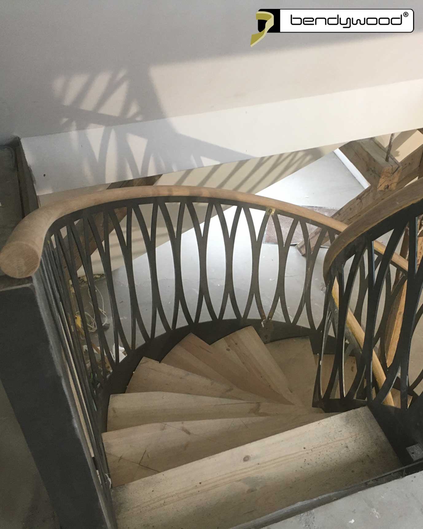 Corrimano rotondi in rovere Bendywood® per scala curva. Montati direttamente su paratia in acciaio. 